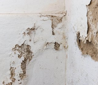 Abblätternde Farbschicht und freiliegende bröckelnde Wandfläche